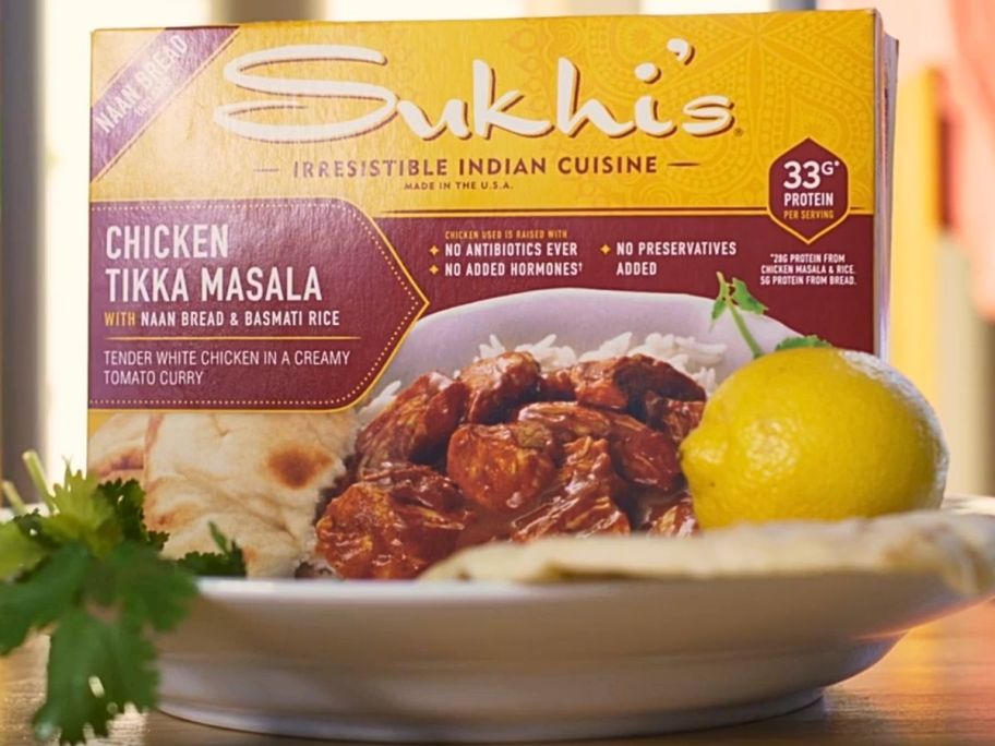 A box of Sukhi Chicken Tikka Masala in a plate with a lemon