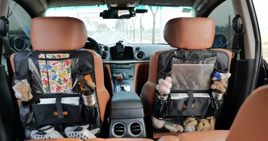 inside of a car with brown leather seats, showing black car seat organizers with a a variety of items in them