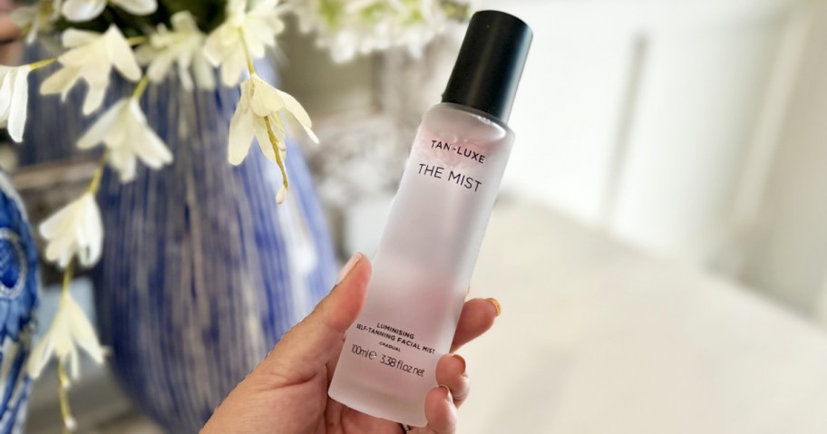 hand holding a bottle of Tan-Luxe Facial Mist
