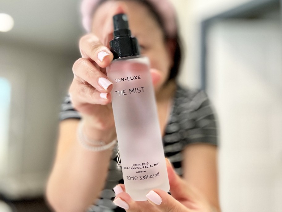 woman holding up a bottle of Tan-Luxe Facial Mist