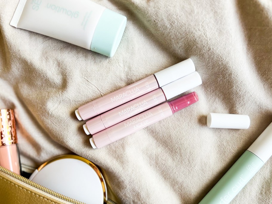 three sticks of Tarte Maracuja Juicy Lip Balms surrounded by other makeup products