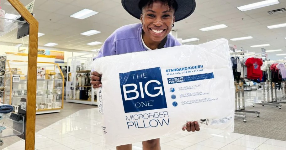 A woman holding a big one pillow in kohl's store