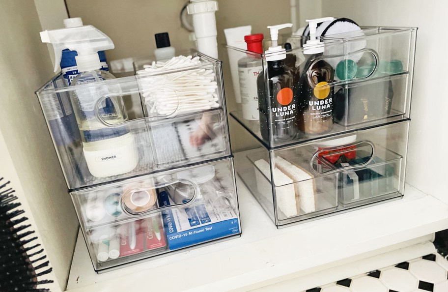 clear storage bins filled with personal care products under bathroom sink