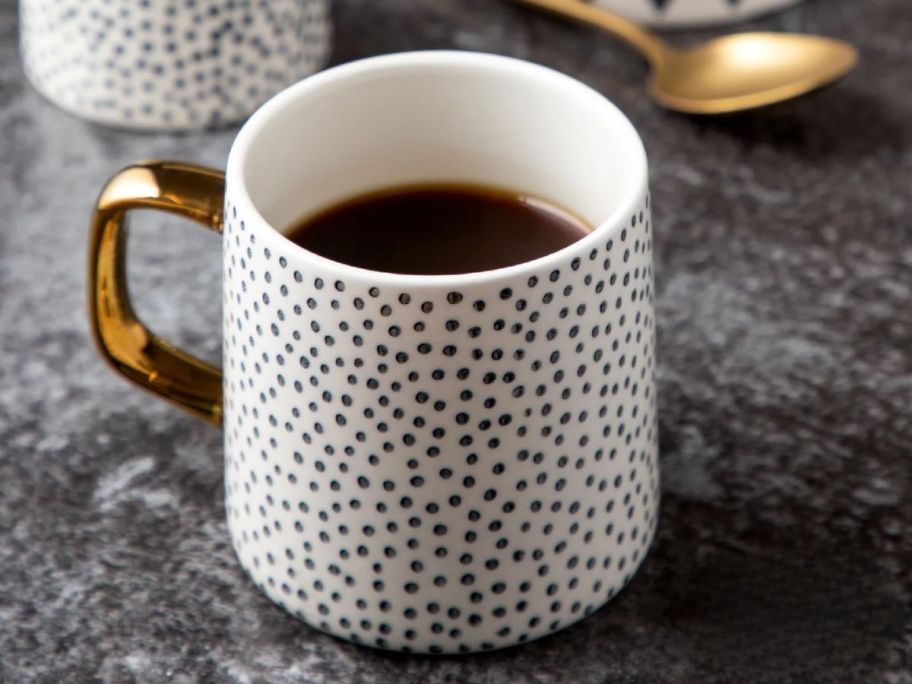 a black and white dotted coffee mug with a gold handle