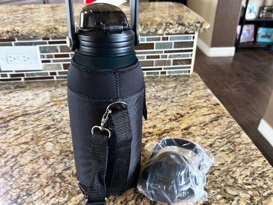 water bottle in black carrier bag on kitchen counter with spare lid