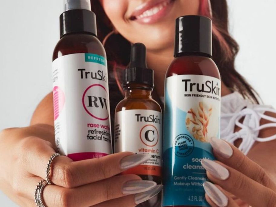 Woman holding 3 bottles of TruSkin Skincare from the Truskin x Kylie gift set