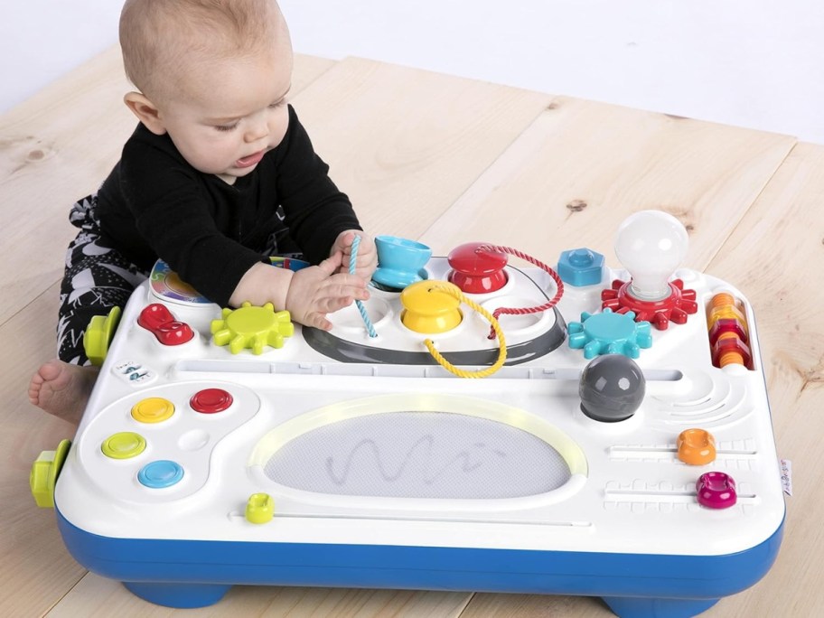 baby playing with the top of an activity center table