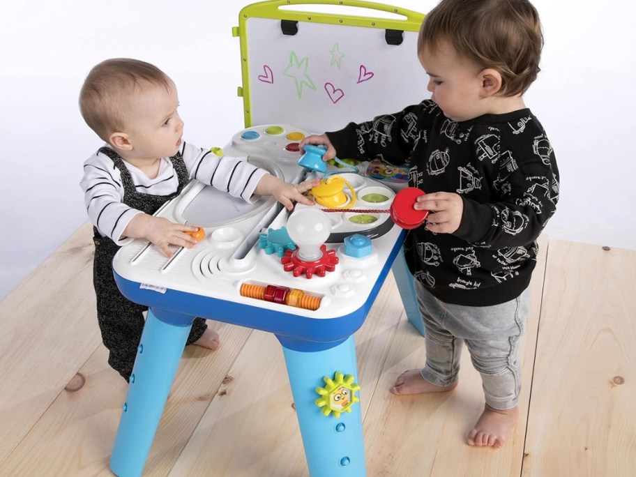 baby and toddler playing with a colorful activity table