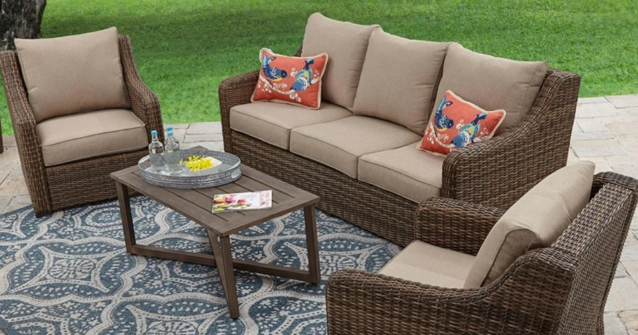 brown wicker outdoor patio furniture set on a rug on a patio