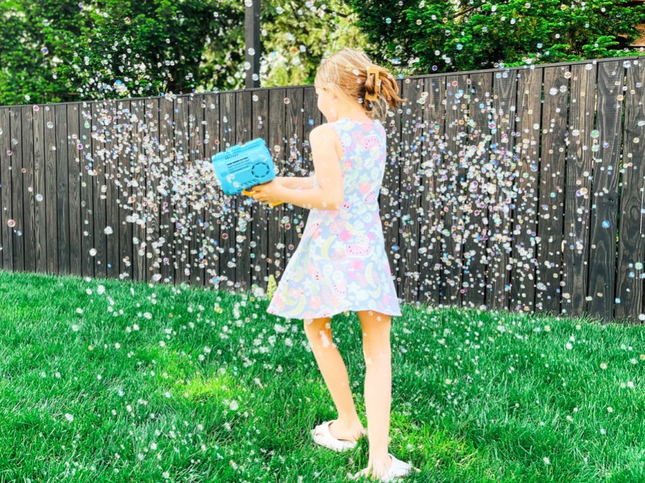girl holding bubble blaster and twirling around in bubbles