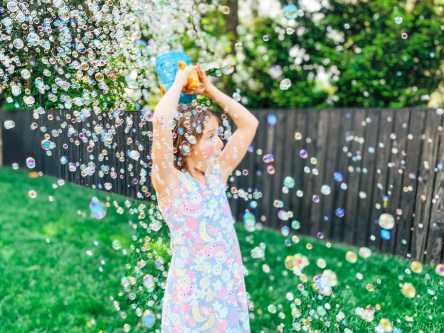 girl surrounded by bubbles and holding bubble blaster over her head