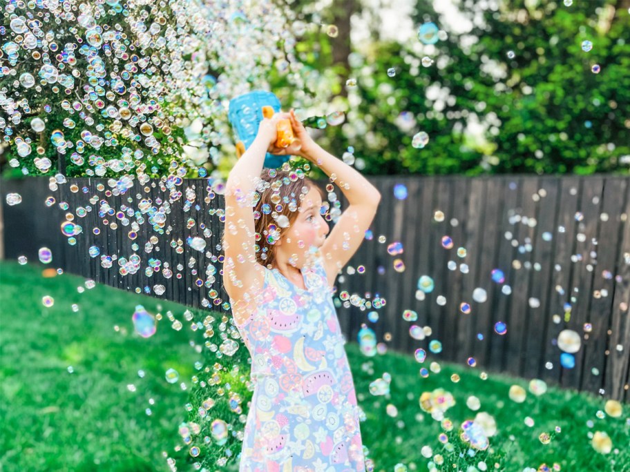 girl surrounded by bubbles and holding bubble blaster over her head