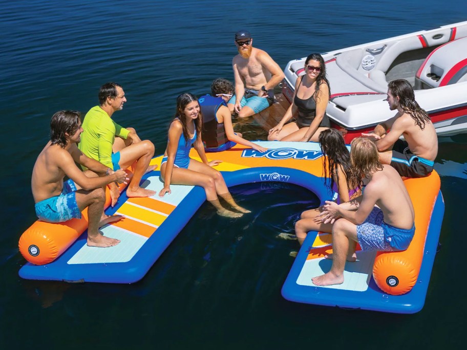 large group of people hanging out on floating dock next to boat