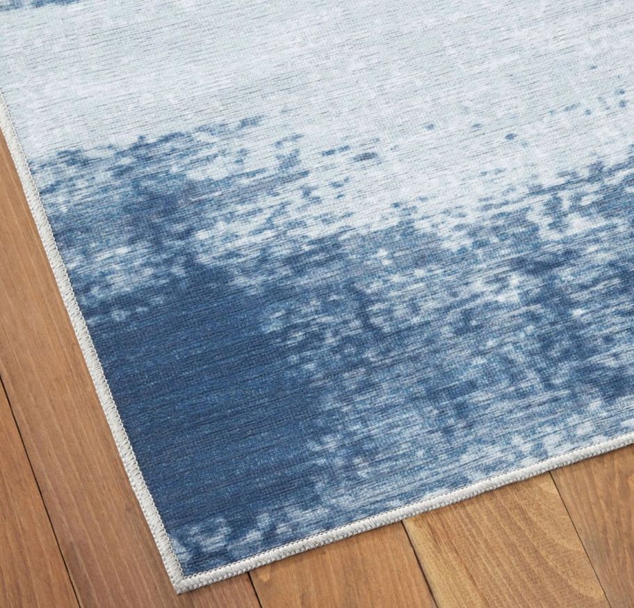 a corner of a blue and gray washable area rug