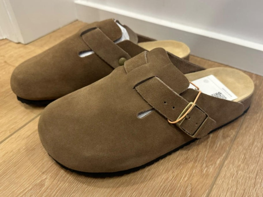 pair of dark brown suede clog mule shoes sitting on the floor