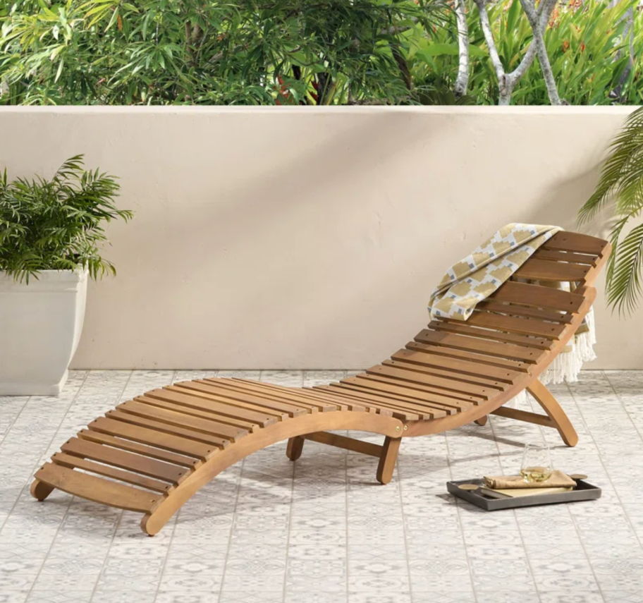 A chaise lounge from the Wayfair Memorial Day Clearance Sale on an outdoor patio