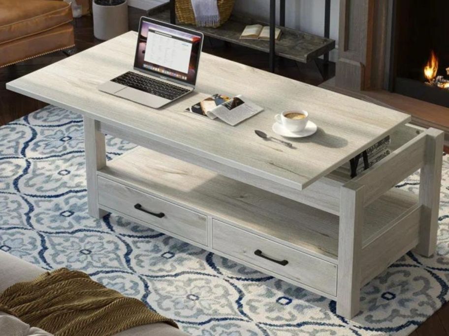 A Millwood Pines Eoghan Lift Top Coffee Table w/ 2 Drawers with a laptop on it and coffee