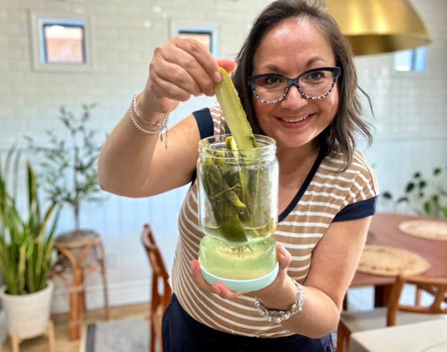 Woman using cool kitchen gadgets and grabbing a pickle out of her White Rhino pickle jar that separates the juice