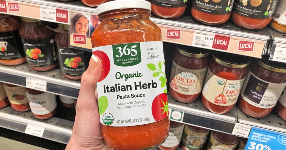 hand holding a jar of Whole Foods Market Organic Pasta Sauce in store