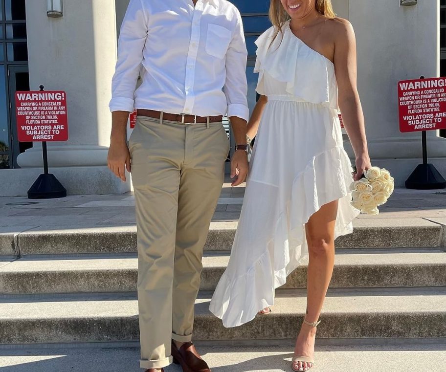 Woman on courthouse steps carrying a bouquet and wearing a Zesica Asymetrical Maxi Dress