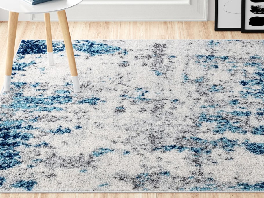 grey and blue abstract area rug on wood floor