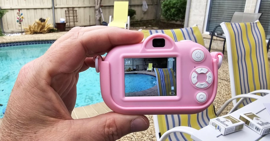 hand holding up a kids pink digital camera