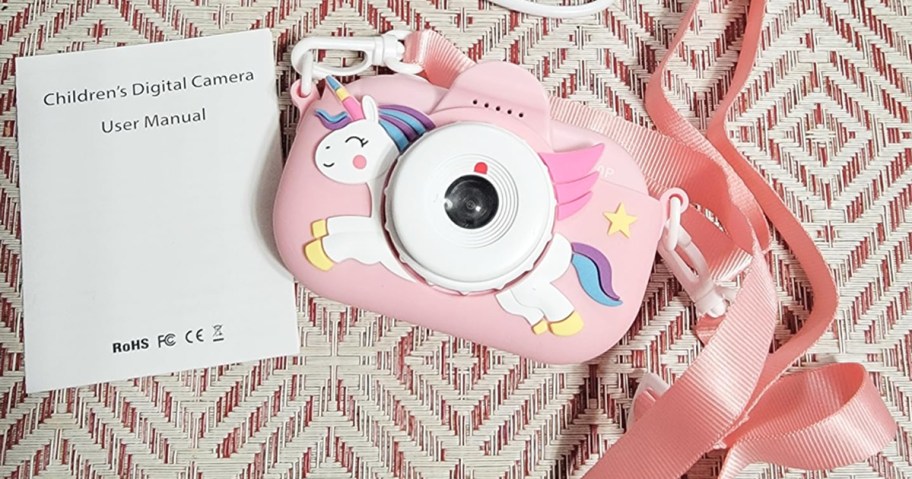pink unicorn camera with strap near instruction booklet