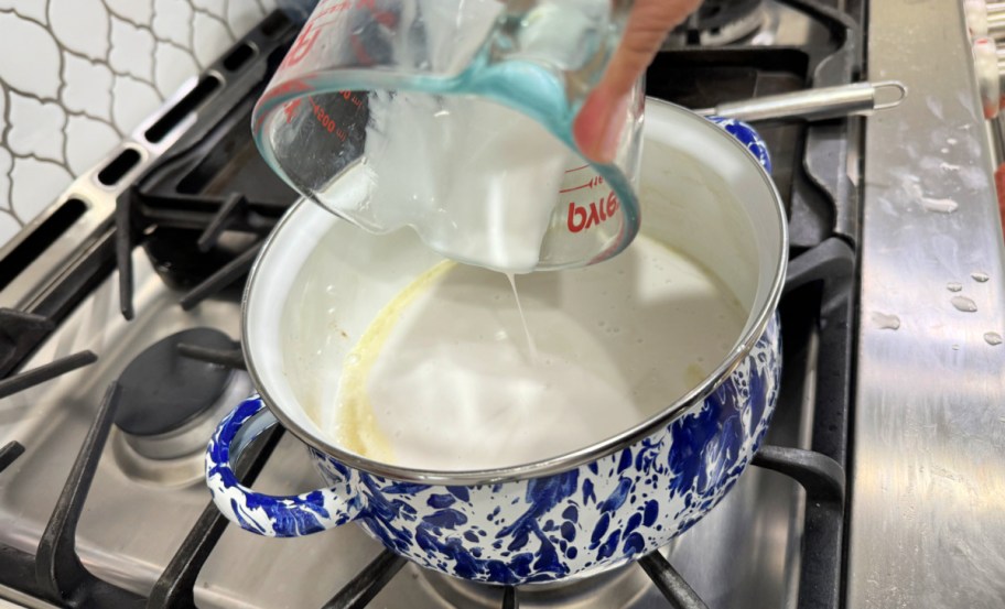 adding coconut milk to a saucepan on the stove
