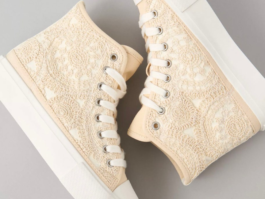 a pair of white crochet shoes laying sideways