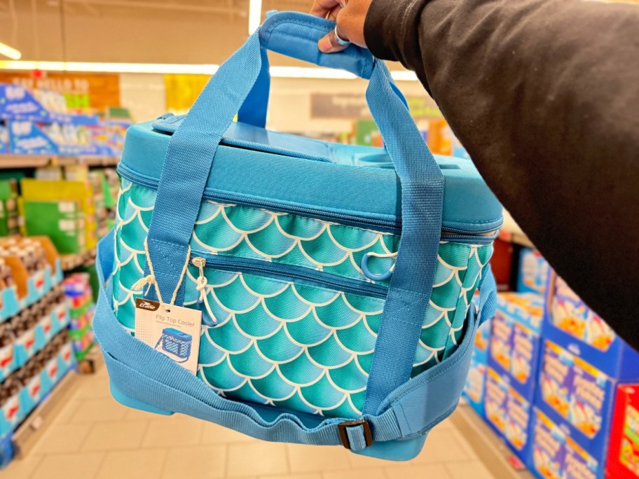 hand holding a blue flip top cooler with mermaid scale print