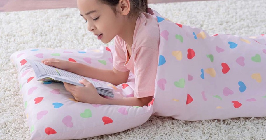 kid inside pink heart sleeping bag reading