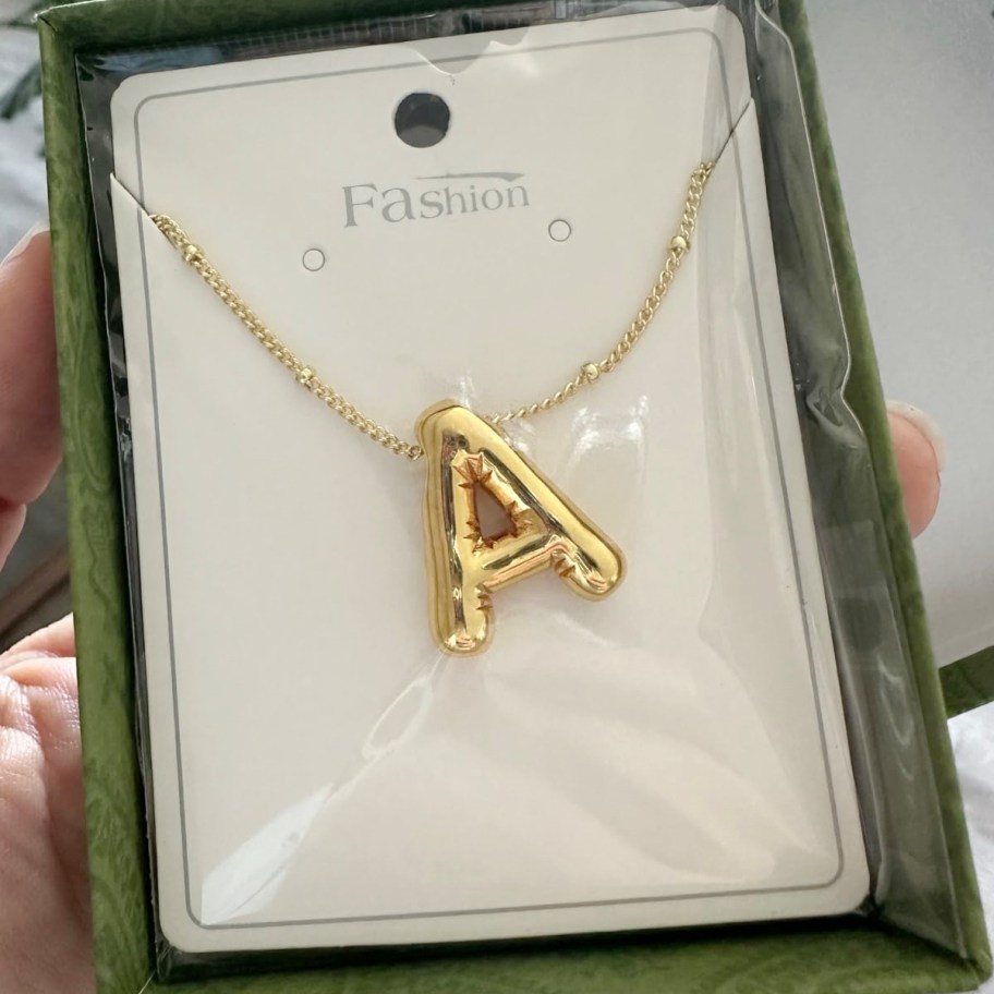 hand holding letter A necklace in box