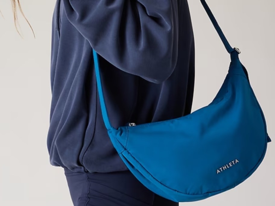 woman carrying a blue Athleta crossbody purse