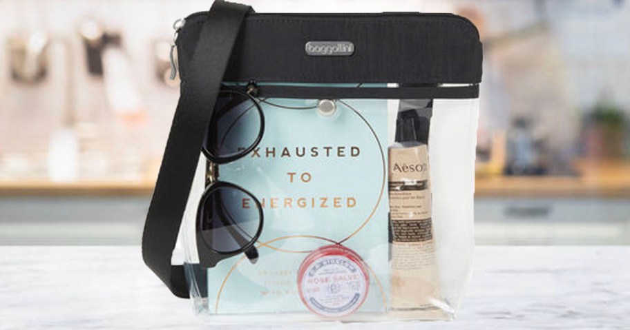 black and clear crossbody bag full of makeup and other products sitting on countertop