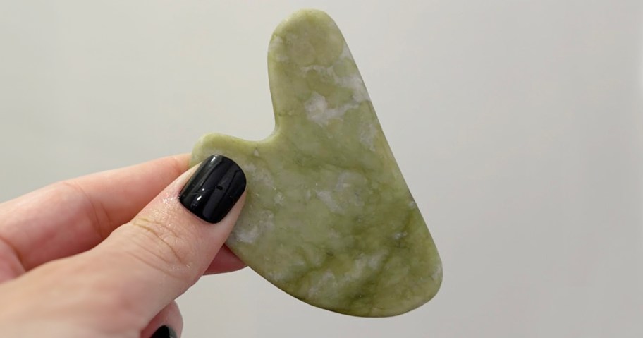 hand holding jade gua sha tool 
