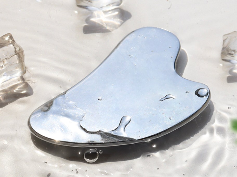 stainless steel gua sha laying in water
