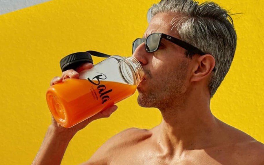 man drinking turmeric drink in bottle