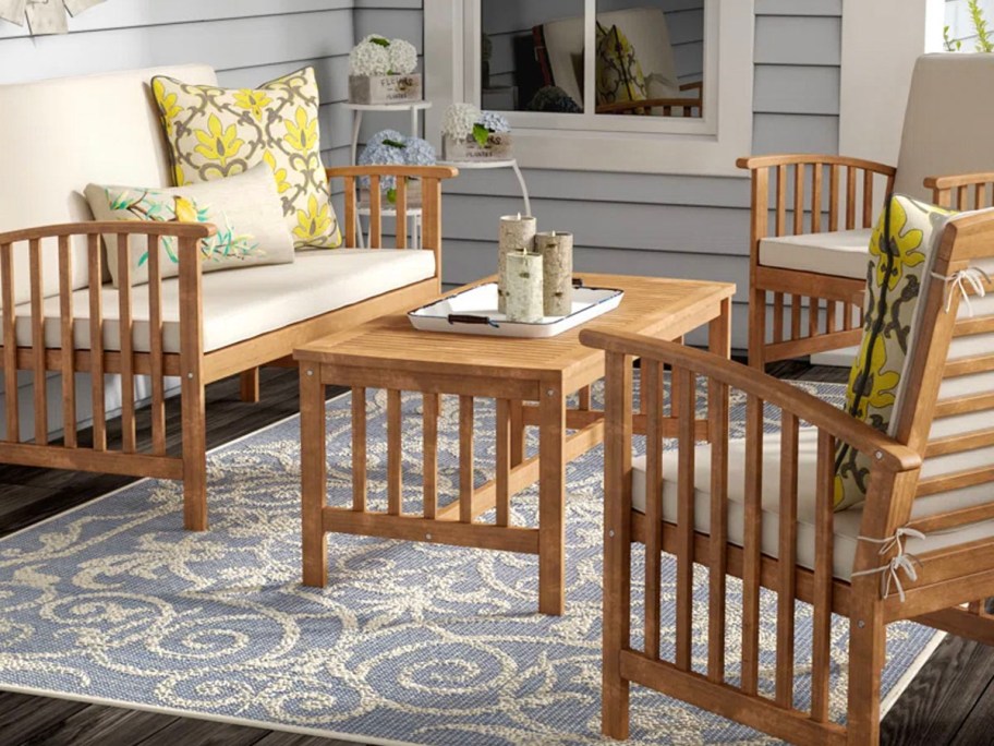 wooden patio set with table, loveseat nad two chairs on porch with whit cushions. 