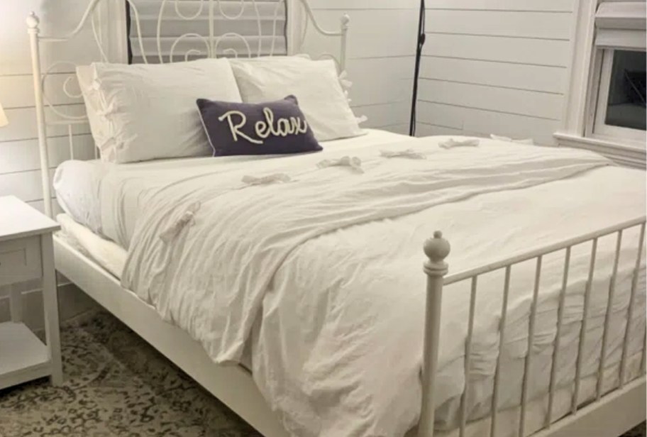 a bed with white bedding including sheets and comforter with a throw pillow