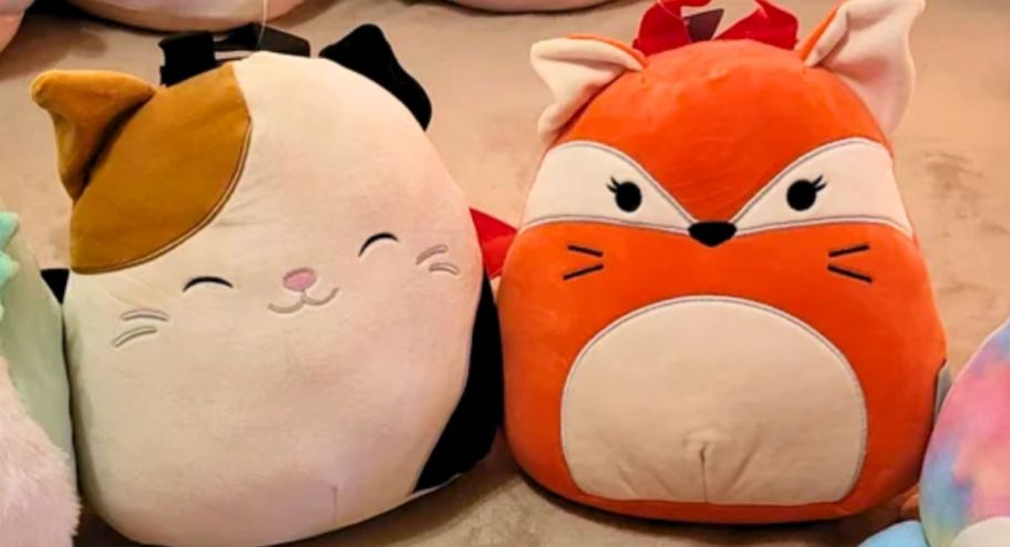  cam and fifi bioworld backpacks sitting on a floor surrounded by squishmallows dolls