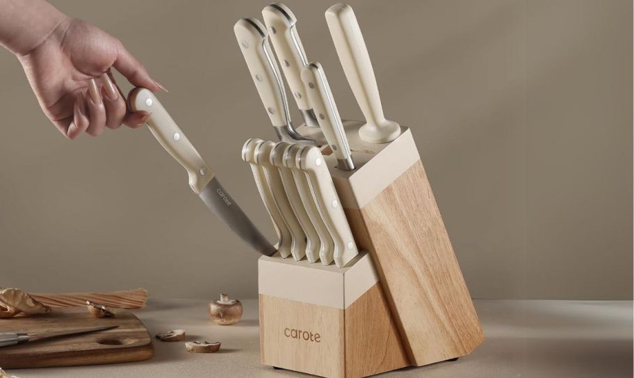 a womans hand grabbing a knife from a wooden knife block