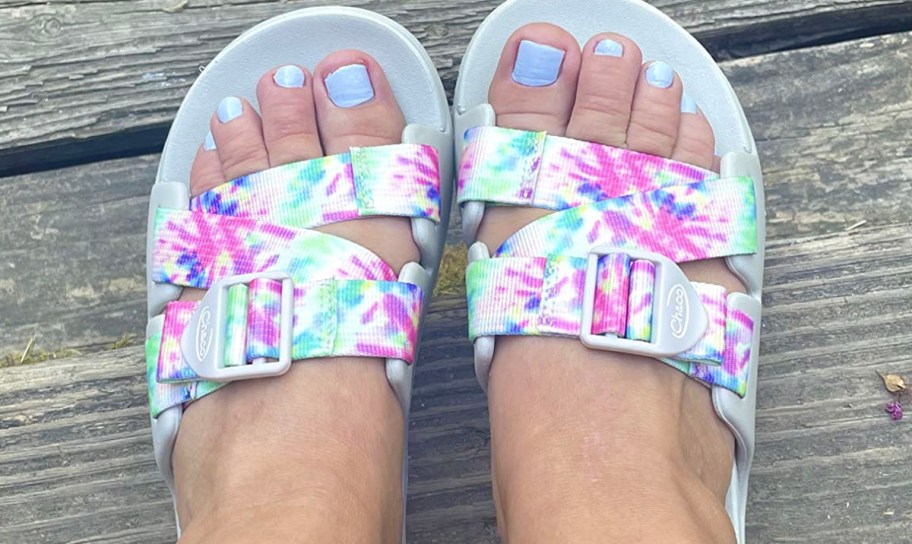 person wearing tie dye white chacos slides