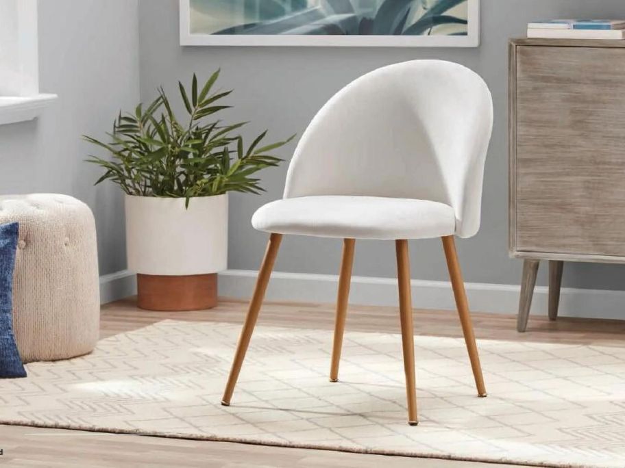 Mainstays Modern Accent Chair, Cream White sitting on carpet with a plant next to it
