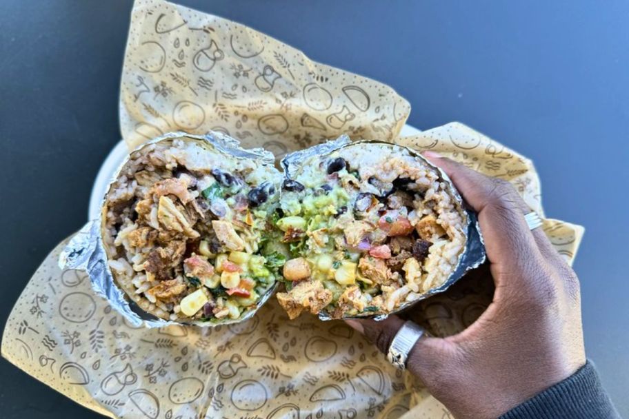 a woman hand holding half a chipotle burrito