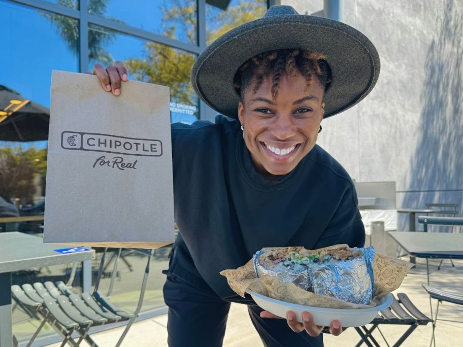woman holding chipotle bag with entree in hands outside