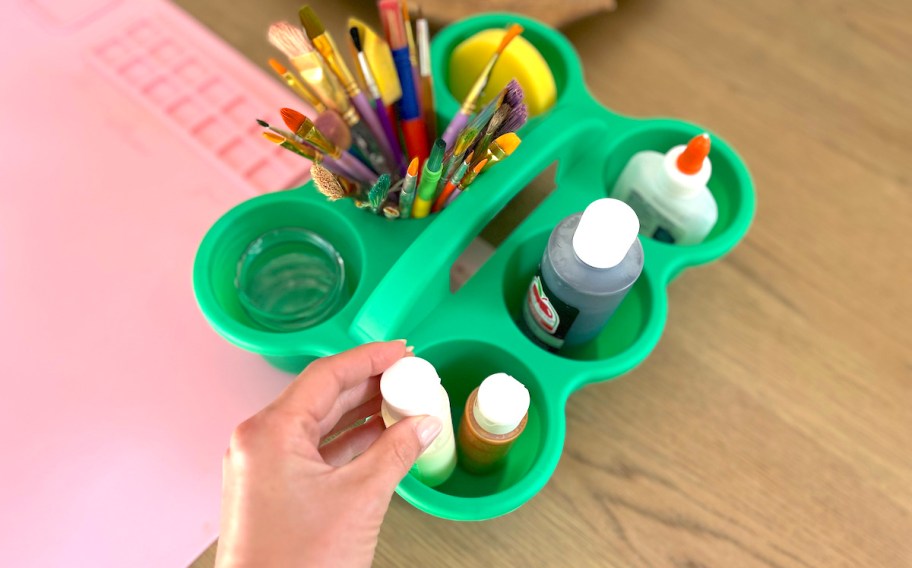 hand putting paint in green cup holder caddy