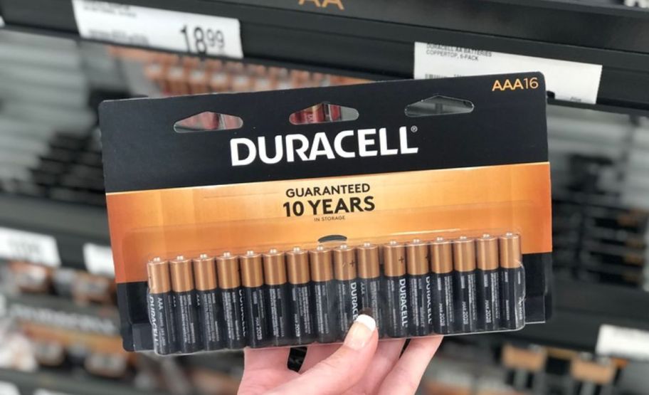 a womans hand holding a 16 count pack of duracell AAA batteries