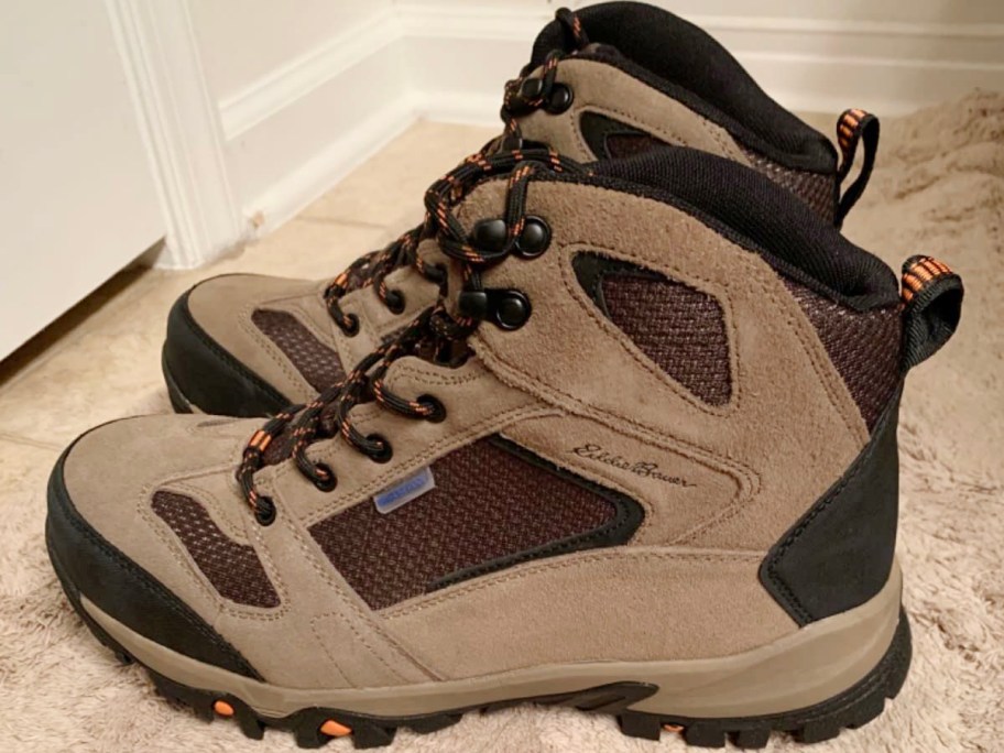 tan and black hiking boots sitting on carpet