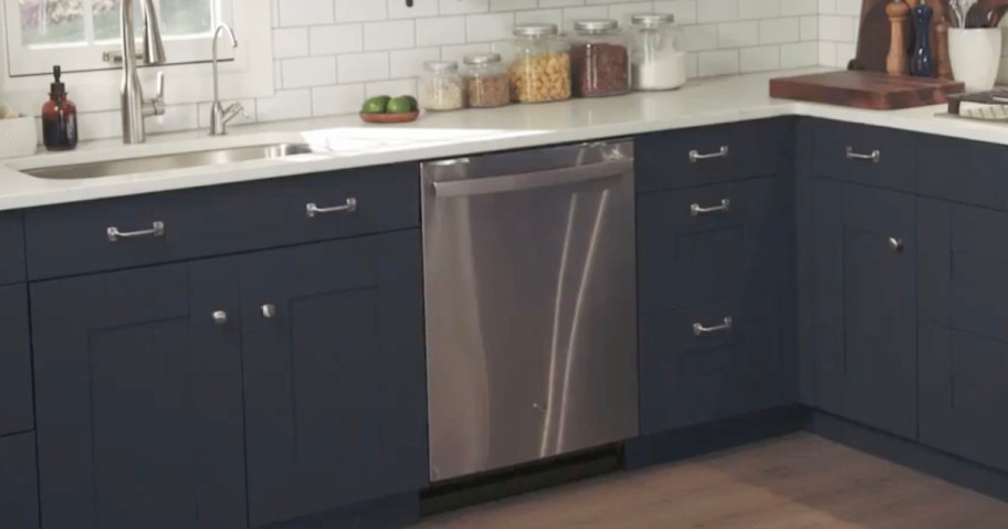 stainless steel dishwasher in between navy cabinets 