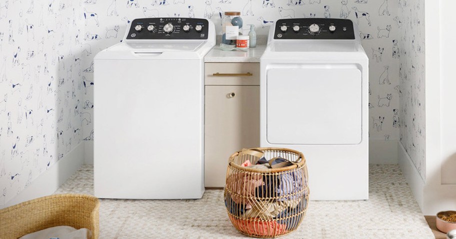 white washer and dryer in laundry room with basket of clothes in front